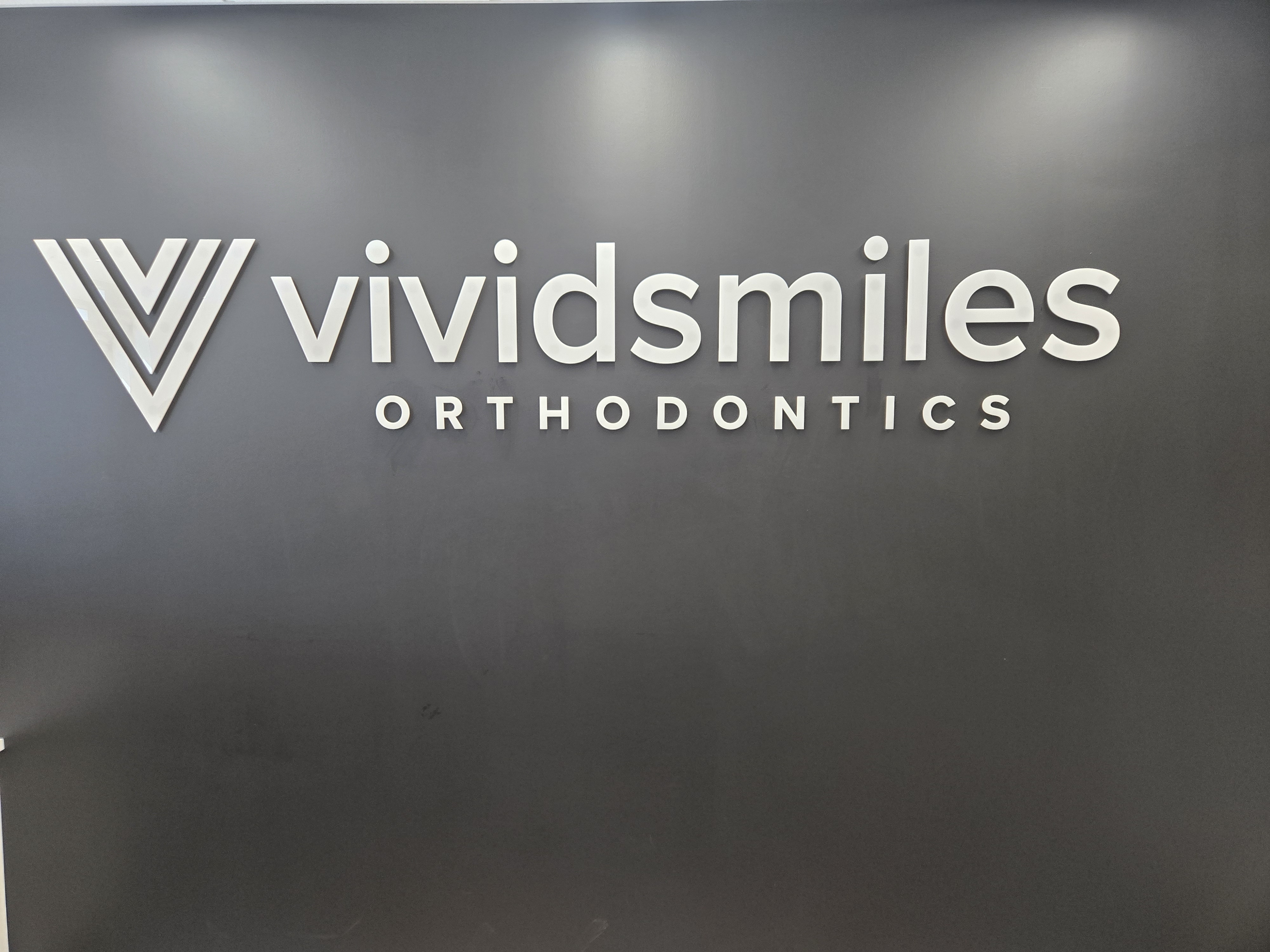 Vivid Smiles Orthodontics logo wall
